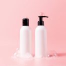 Shampoo and hair conditioner bottle with soapy bubbles. Plastic white packing with black cap beauty hair care cosmetic packaging mockup